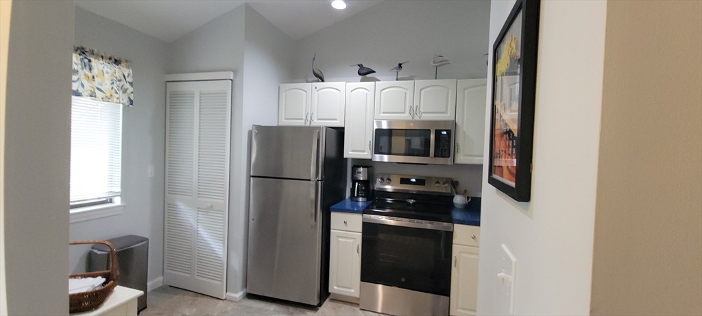 150 Eaton Lane, Unit 150 Brewster, MA 02631 - Photo 9 of 20 a kitchen with stainless steel appliances a refrigerator a stove and white cabinets