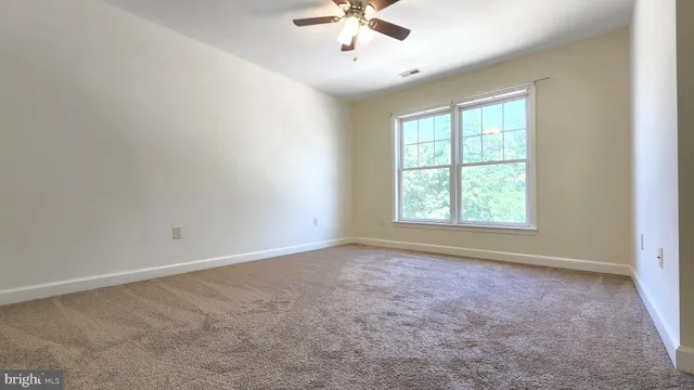 an empty room with windows and ceiling fan