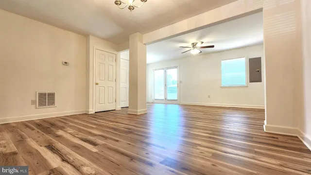 a view of an empty room with window and wooden floor