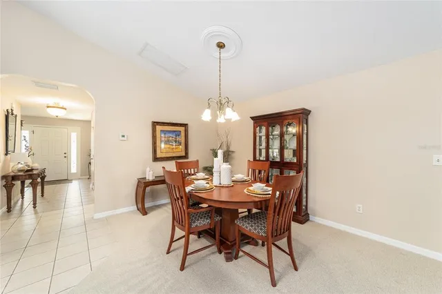 a view of a dining room and livingroom with furniture wooden floor a rug a chandelier and a mirror