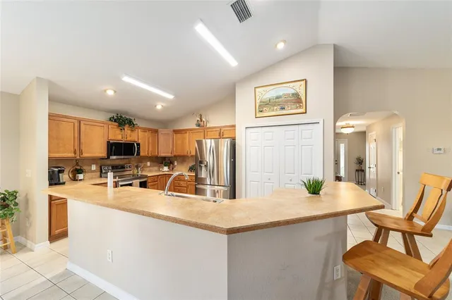 a kitchen that has a lot of white cabinets and stainless steel appliances