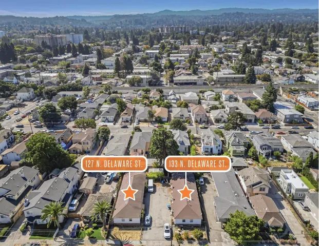 an aerial view of residential houses with outdoor space and trees
