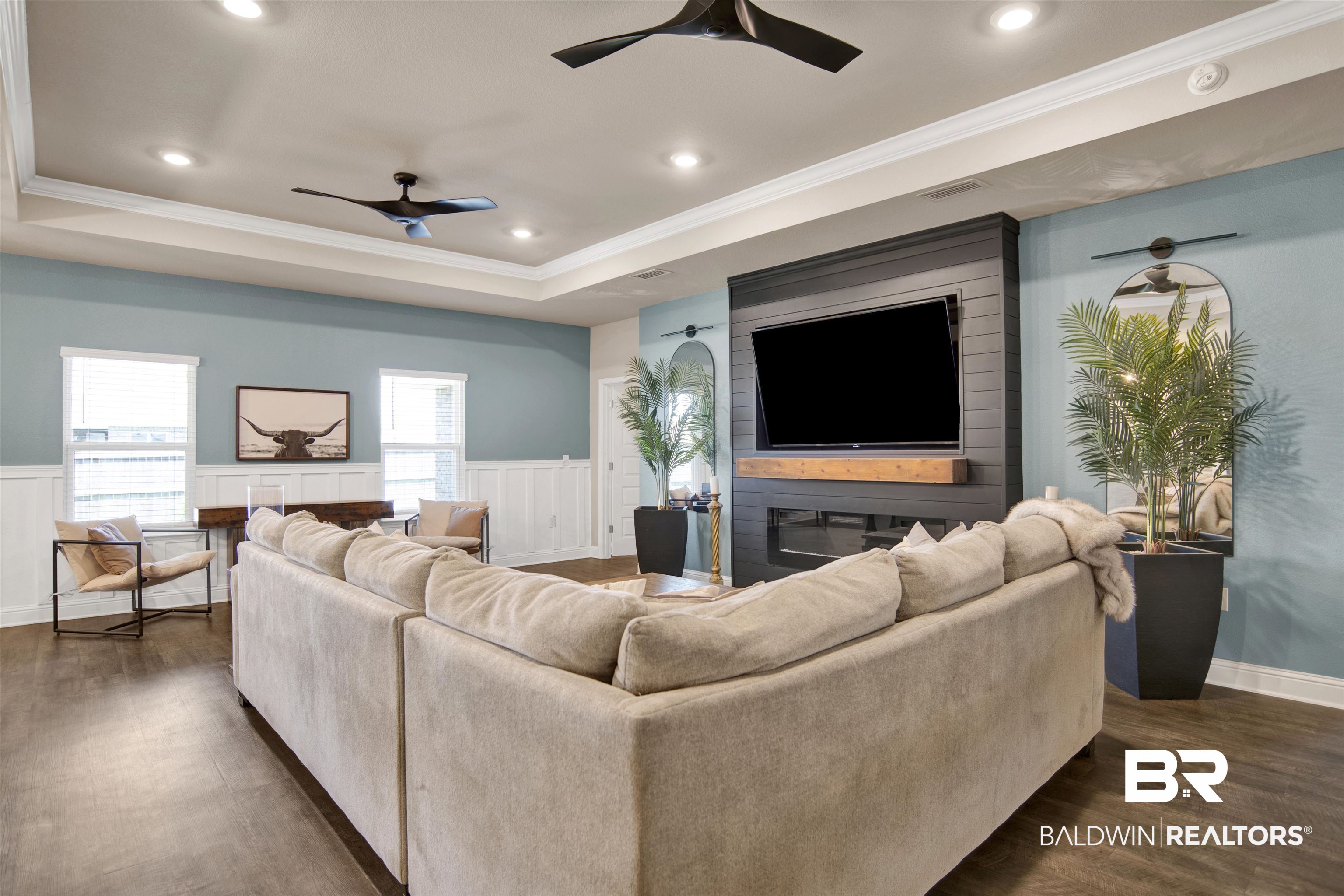 8493 Bronze Lane Foley, AL 36535 - Photo 7 of 38 Living area featuring wood-finish flooring, a tray ceiling with recessed lighting and two ceiling fans, and wainscoting