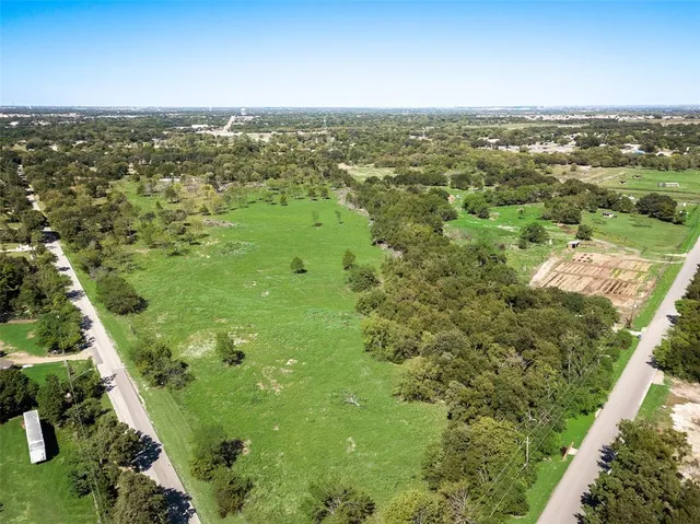 an aerial view of residential houses with outdoor space and trees