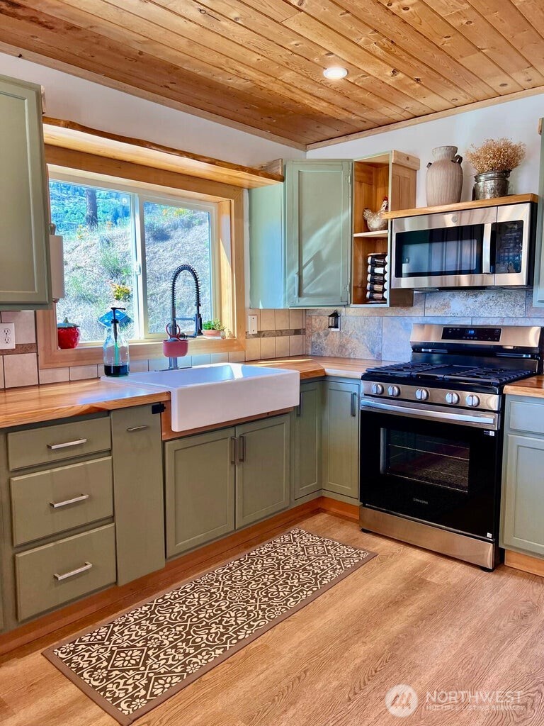 3705 Hope Way Kettle Falls, WA 99141 - Photo 11 of 37 a kitchen with stainless steel appliances granite countertop a stove a sink dishwasher and cabinets with wooden floor
