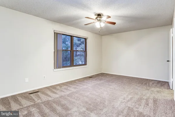 an empty room with chandelier fan and windows
