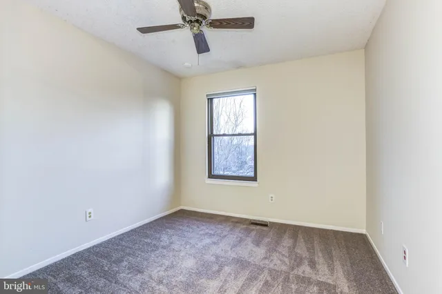an empty room with a window and a fan