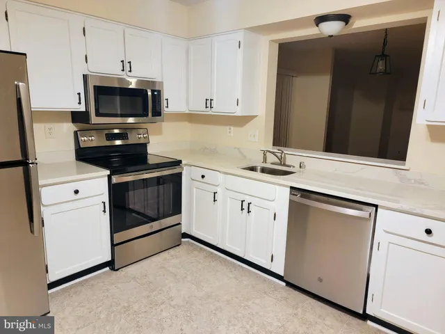 a kitchen with cabinets stainless steel appliances and sink