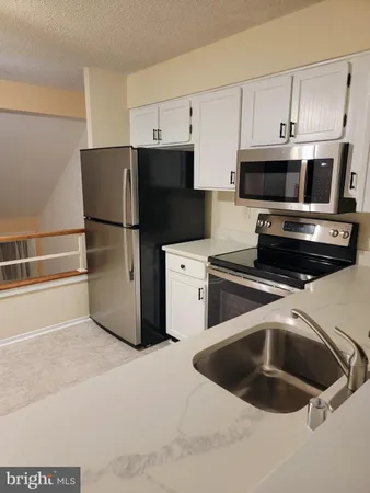 a kitchen with a refrigerator sink and cabinets