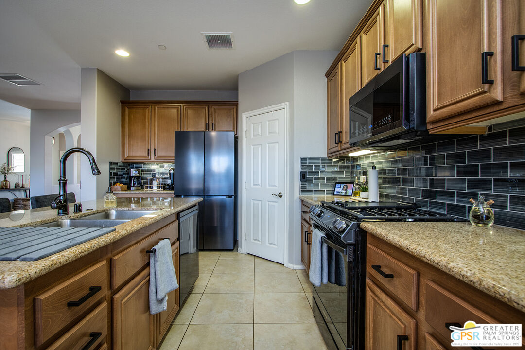 56166 Nez Perce Trail Yucca Valley, CA 92284 - Photo 16 of 54 a kitchen with stainless steel appliances granite countertop a sink stove and refrigerator