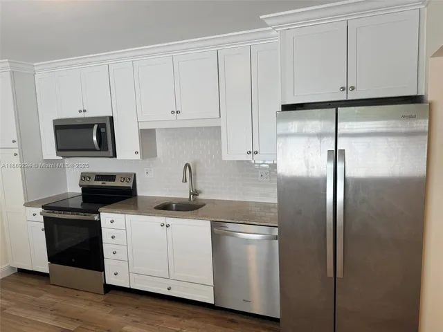 a kitchen with stainless steel appliances granite countertop a refrigerator sink and white cabinets