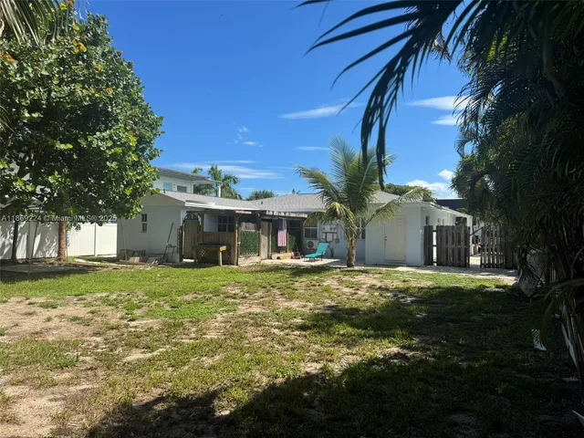 a backyard of a house with table and chairs and a large tree