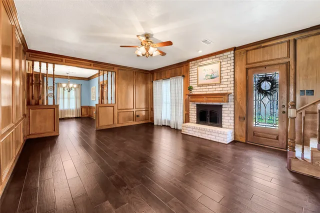 an empty room with wooden floor fireplace and windows