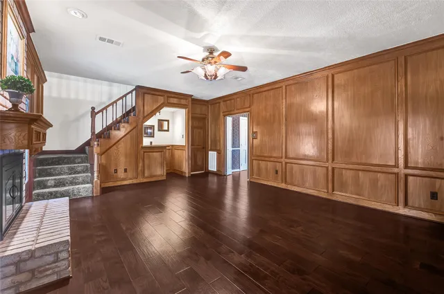 a view of an empty room with wooden floor and a ceiling fan