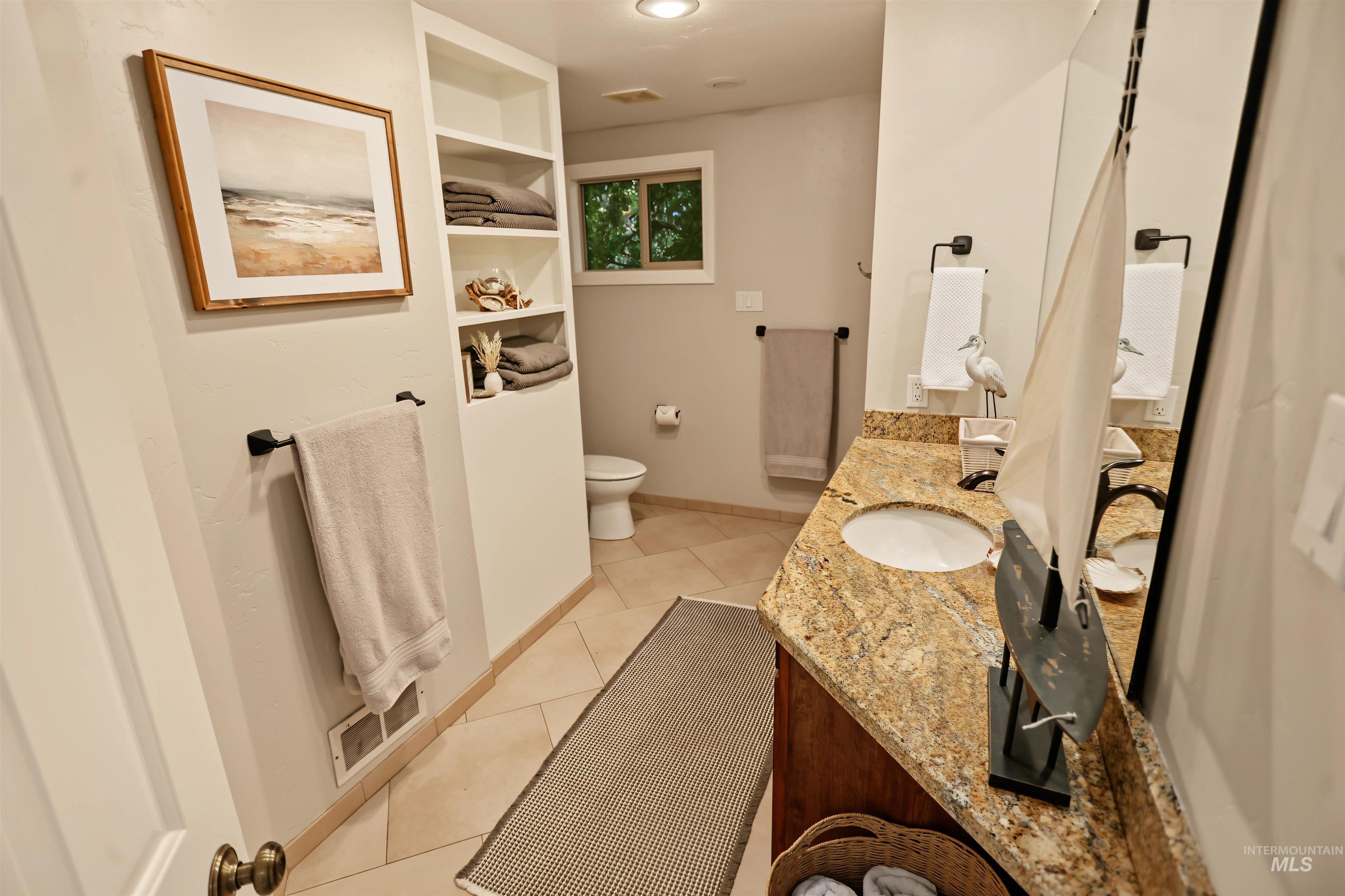 508 East Elm Avenue Parma, ID 83660 - Photo 30 of 50 Built-in shelving, tile flooring, window with natural light, vanity with granite countertop and integrated sink, and an overhead light fixture