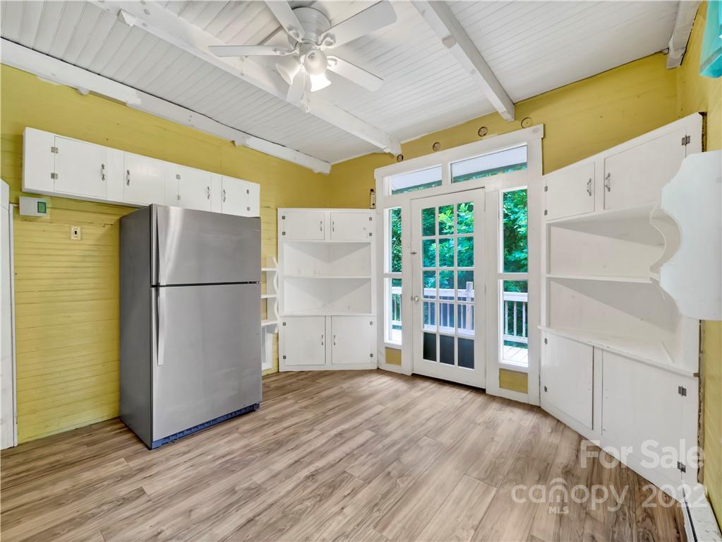 2731 Redmon Road Marshall, NC 28753 - Photo 23 of 43 a view of an empty room with wooden floor and a kitchen