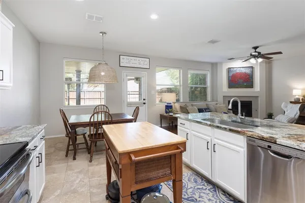 a open kitchen with stainless steel appliances granite countertop a stove a sink a microwave a dining table and chairs with wooden floor