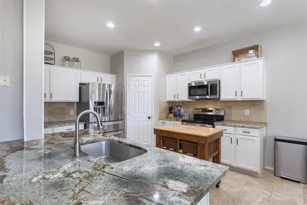 a kitchen with stainless steel appliances granite countertop a sink a stove and a refrigerator