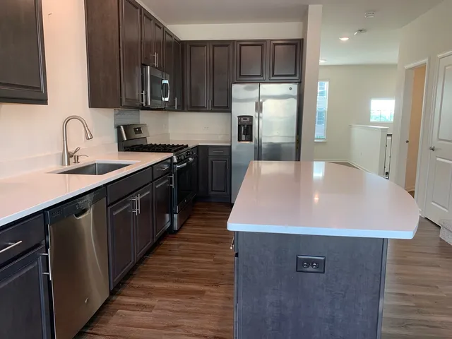 a kitchen with stainless steel appliances granite countertop a sink a refrigerator and a stove