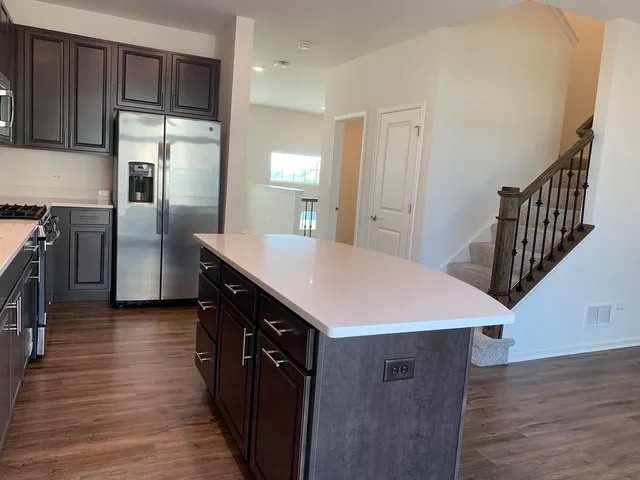 a kitchen with kitchen island a counter top space wooden floor and stainless steel appliances