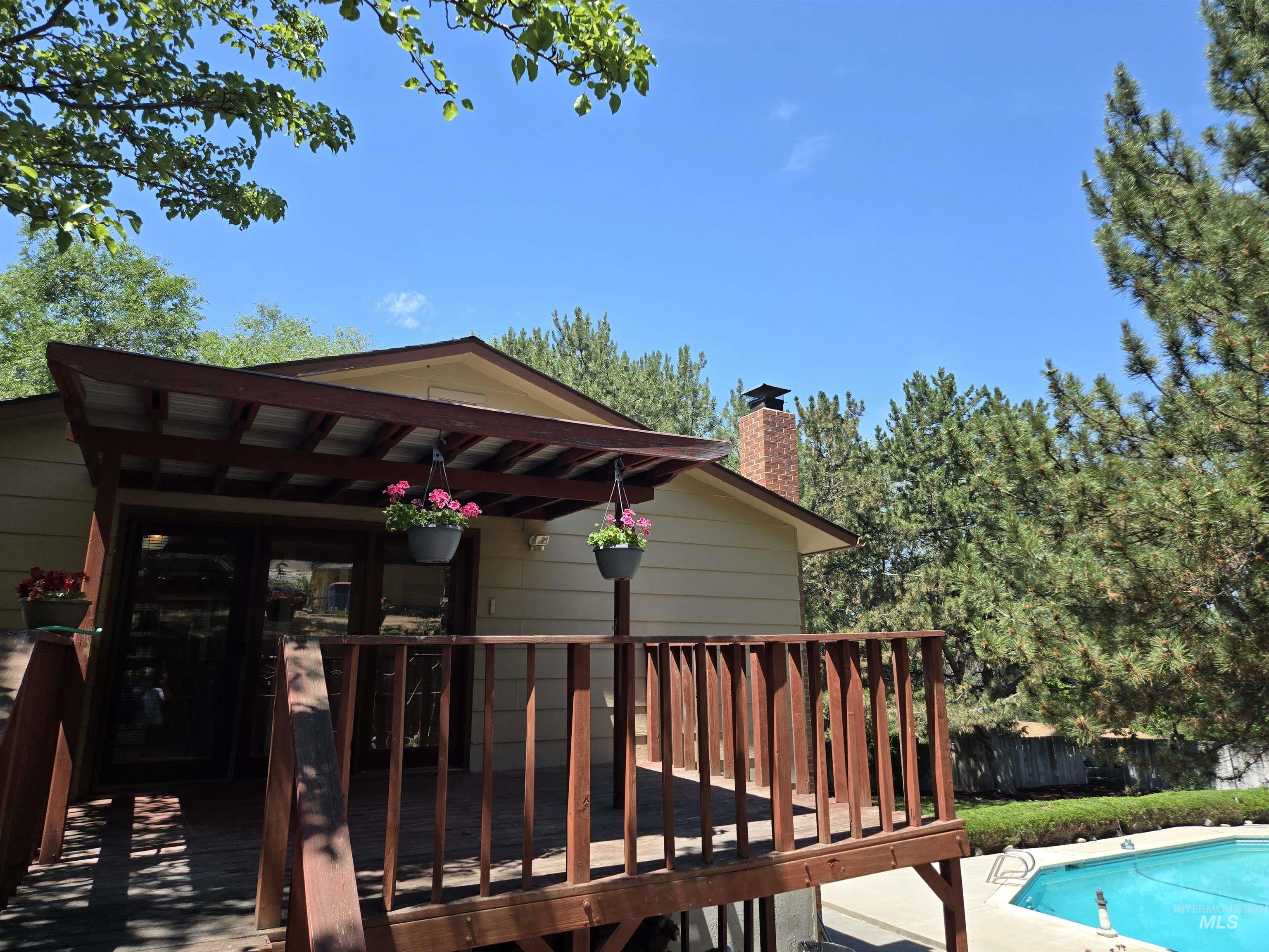 12050 West Hidden Valley Rim Road Boise, ID 83709 - Photo 7 of 39 Raised wooden deck featuring a covered patio, sliding glass doors, and direct access to an in-ground swimming pool