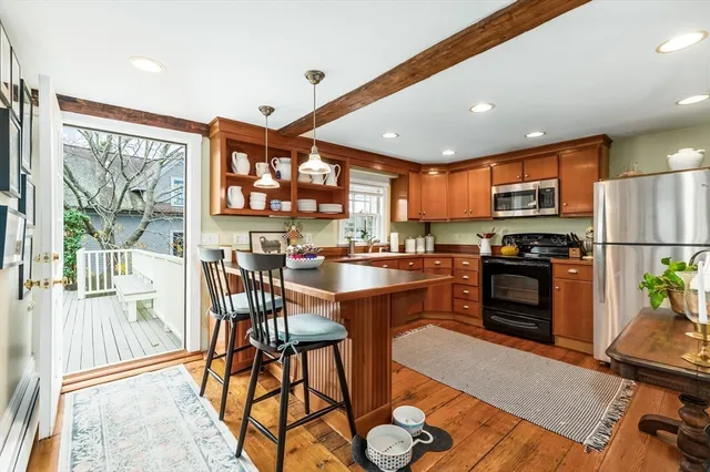 a kitchen with stainless steel appliances granite countertop a stove top oven a sink dishwasher a dining table and chairs with wooden floor