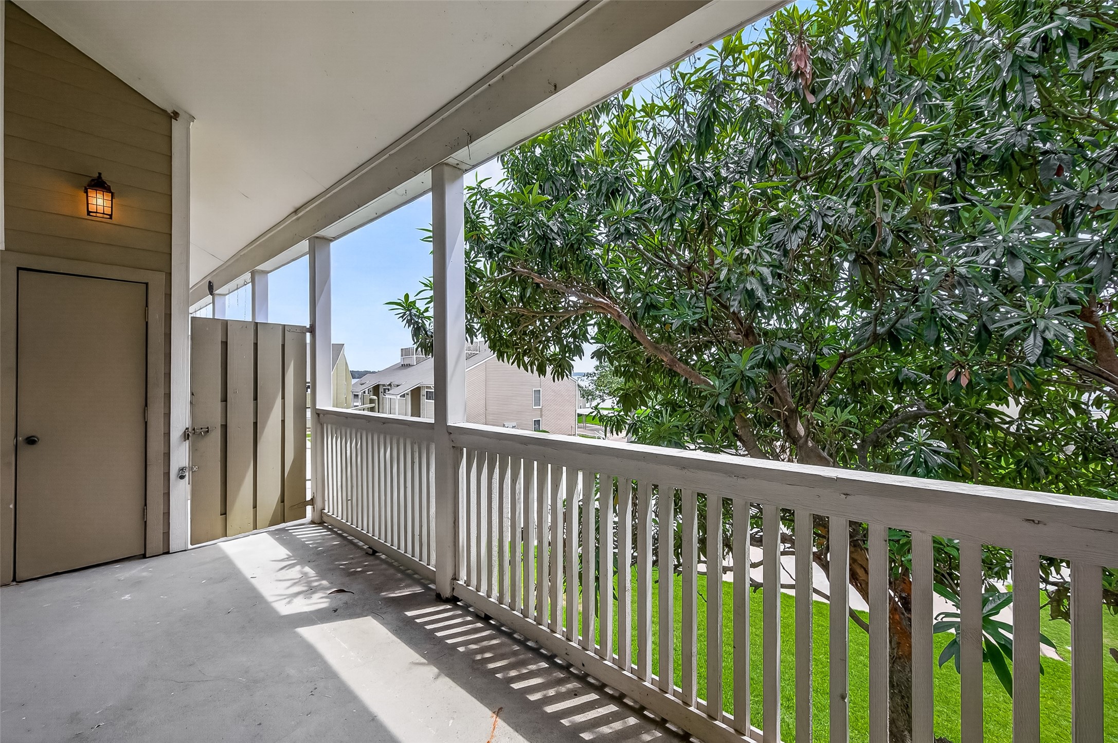 180 April Point Drive South Conroe, TX 77356 - Photo 11 of 39 This photo showcases a covered balcony with white railings, offering a view of lush greenery and nearby buildings. It's a serene outdoor space perfect for relaxation.