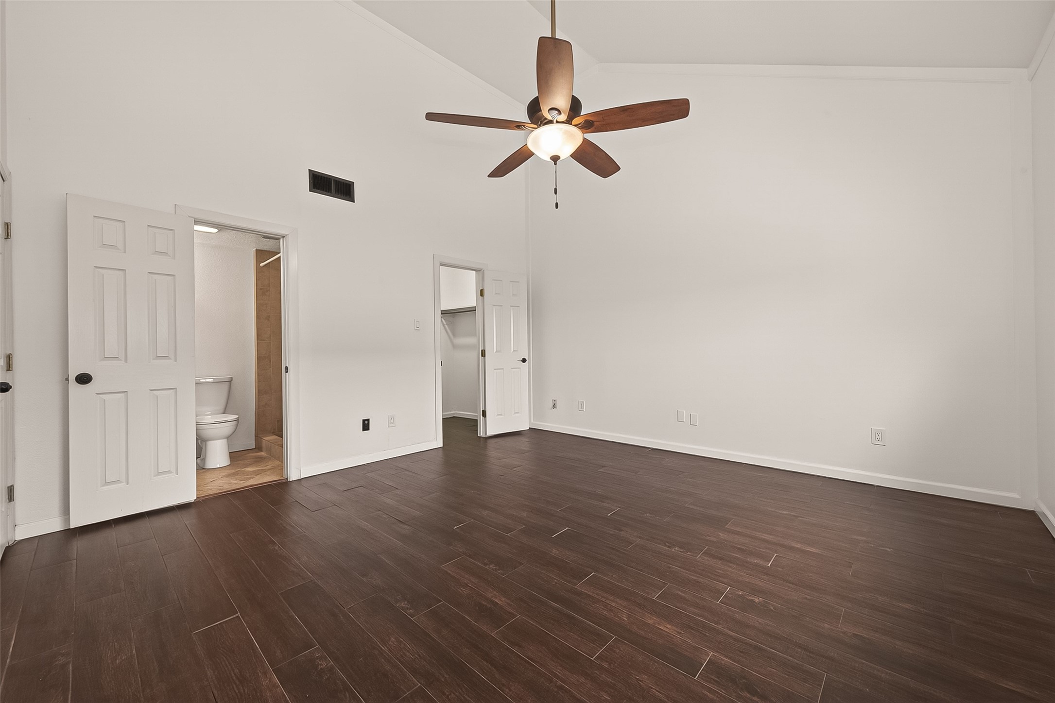 180 April Point Drive South Conroe, TX 77356 - Photo 18 of 39 This spacious bedroom features dark wood flooring, a ceiling fan, and ample natural light. It includes an en-suite bathroom and a walk-in closet, providing both comfort and convenience.