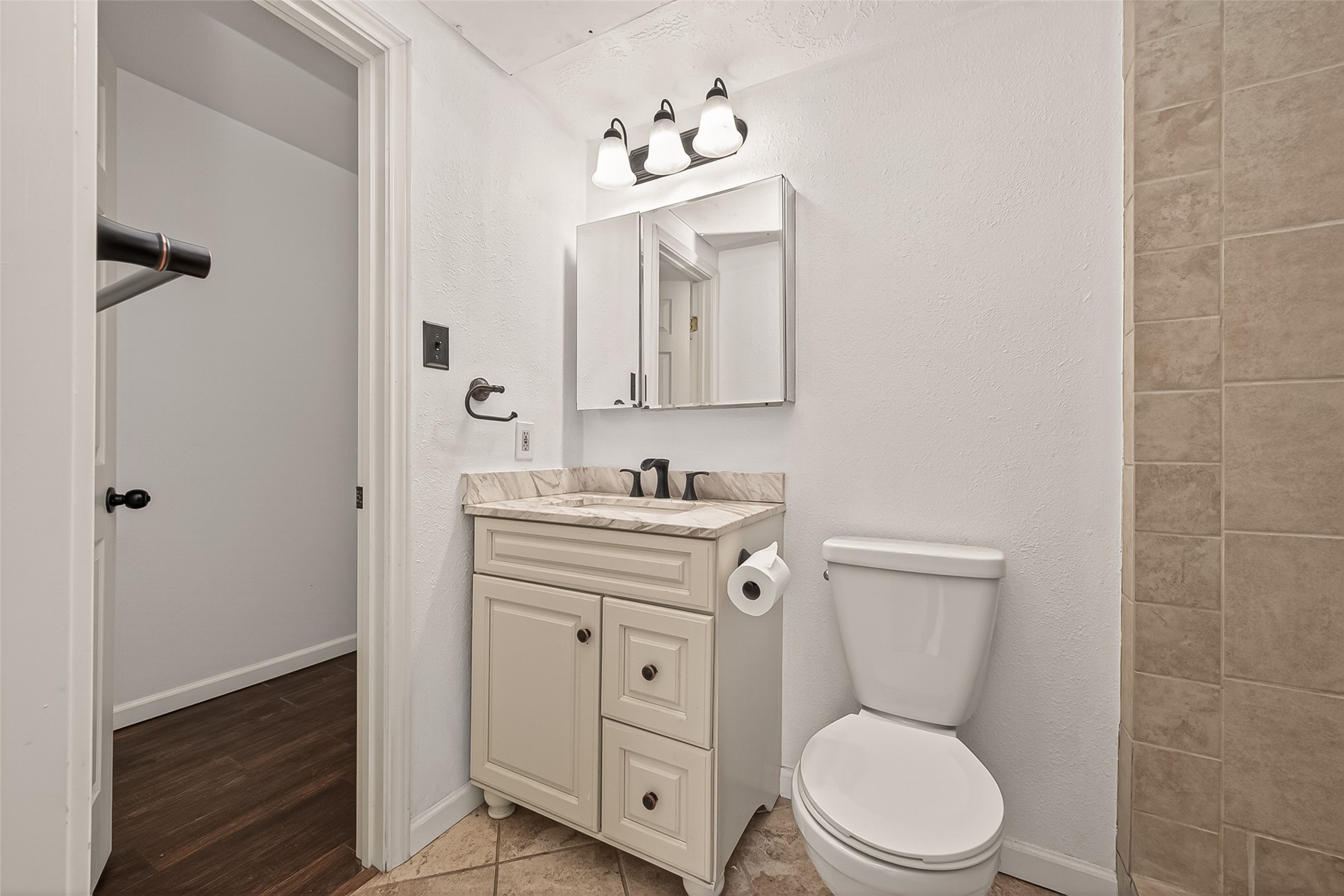180 April Point Drive South Conroe, TX 77356 - Photo 19 of 39 This primary bathroom features a compact layout with a white vanity, granite countertop, and a wall-mounted mirror. It includes a toilet and a shower area with beige tile accents, providing a clean and functional space.