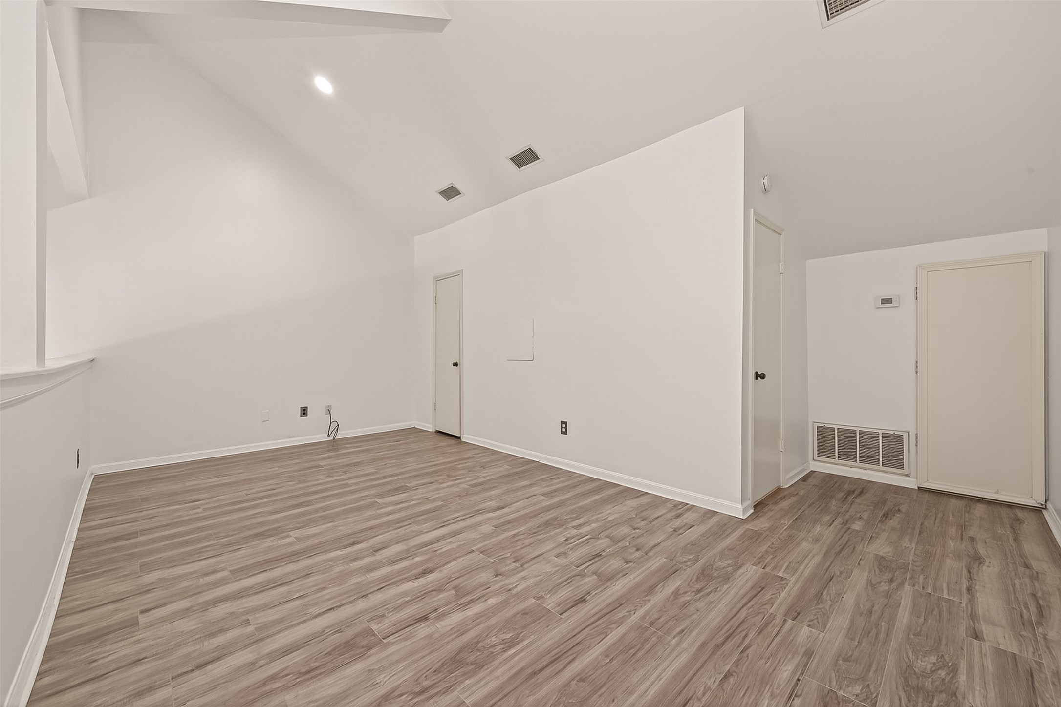180 April Point Drive South Conroe, TX 77356 - Photo 30 of 39 This room features high vaulted ceilings and modern wood-look flooring. It offers a bright, open space with multiple doors for convenient access, perfect for a versatile living area or office.