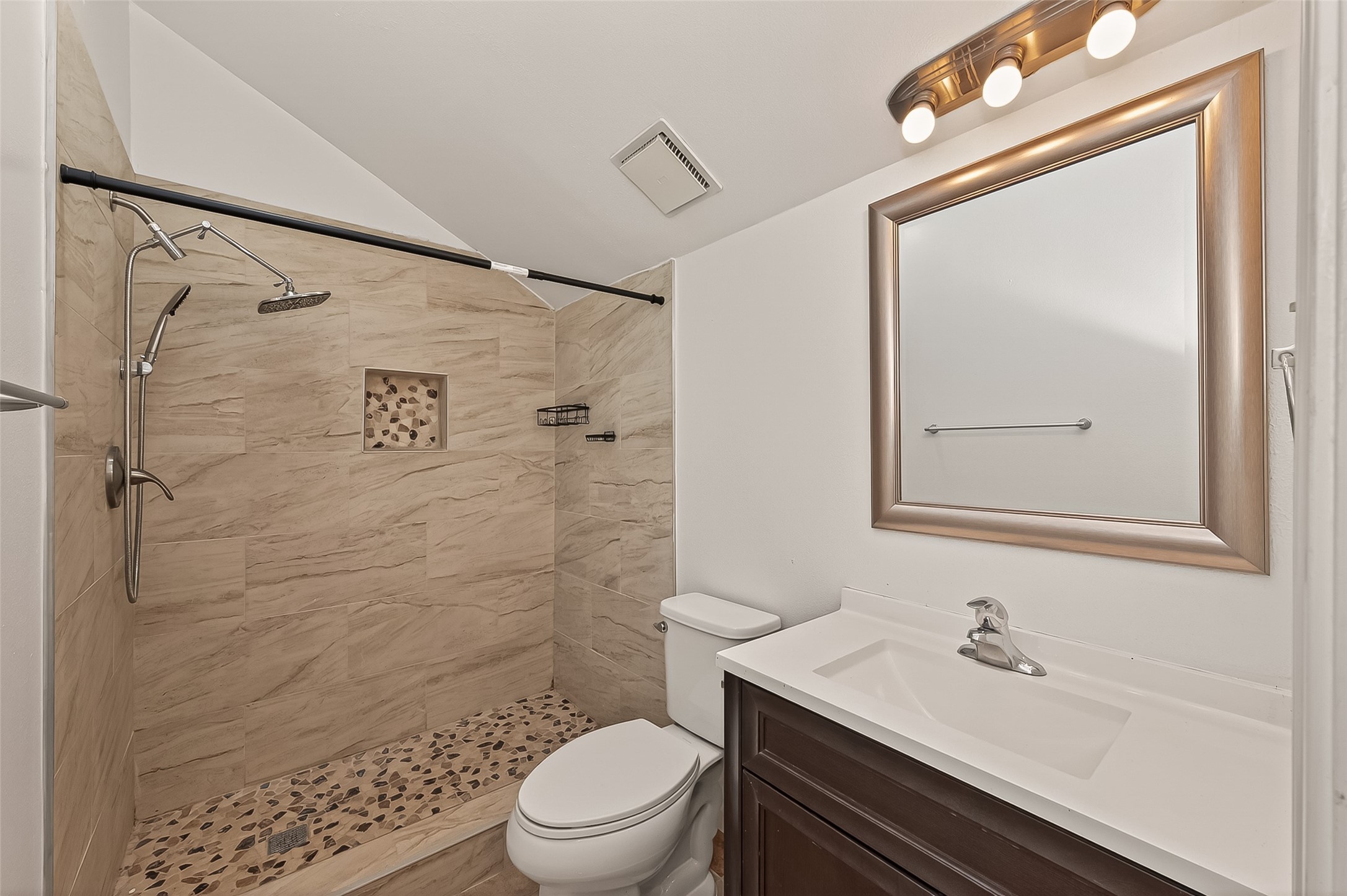 180 April Point Drive South Conroe, TX 77356 - Photo 31 of 39 This second bathroom features a modern walk-in shower with stone-tiled flooring and wall accents, a sleek vanity with a mirror, and a convenient overhead light fixture.