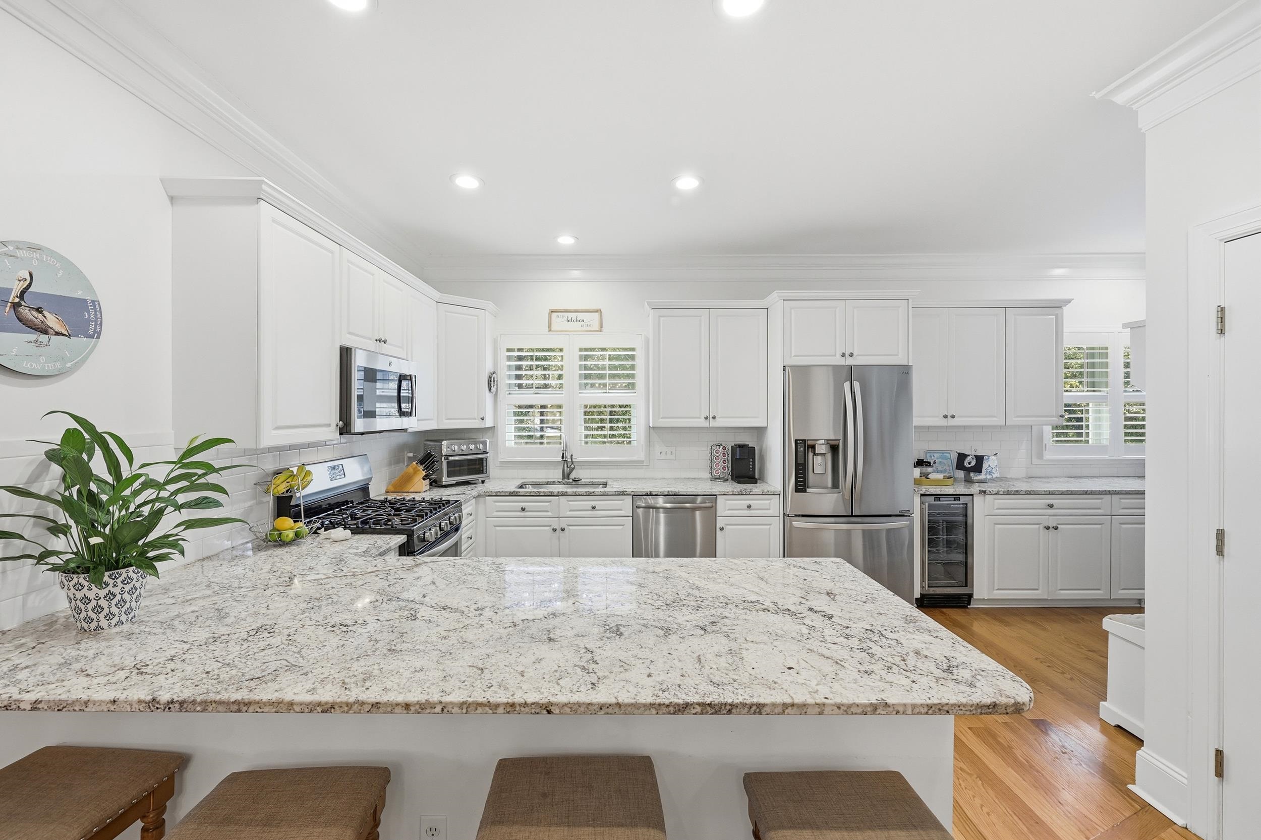 213 Old Carriage Loop Georgetown, SC 29440 - Photo 14 of 40 Kitchen featuring decorative backsplash, a kitchen bar, light stone countertops, crown molding, and recessed lighting