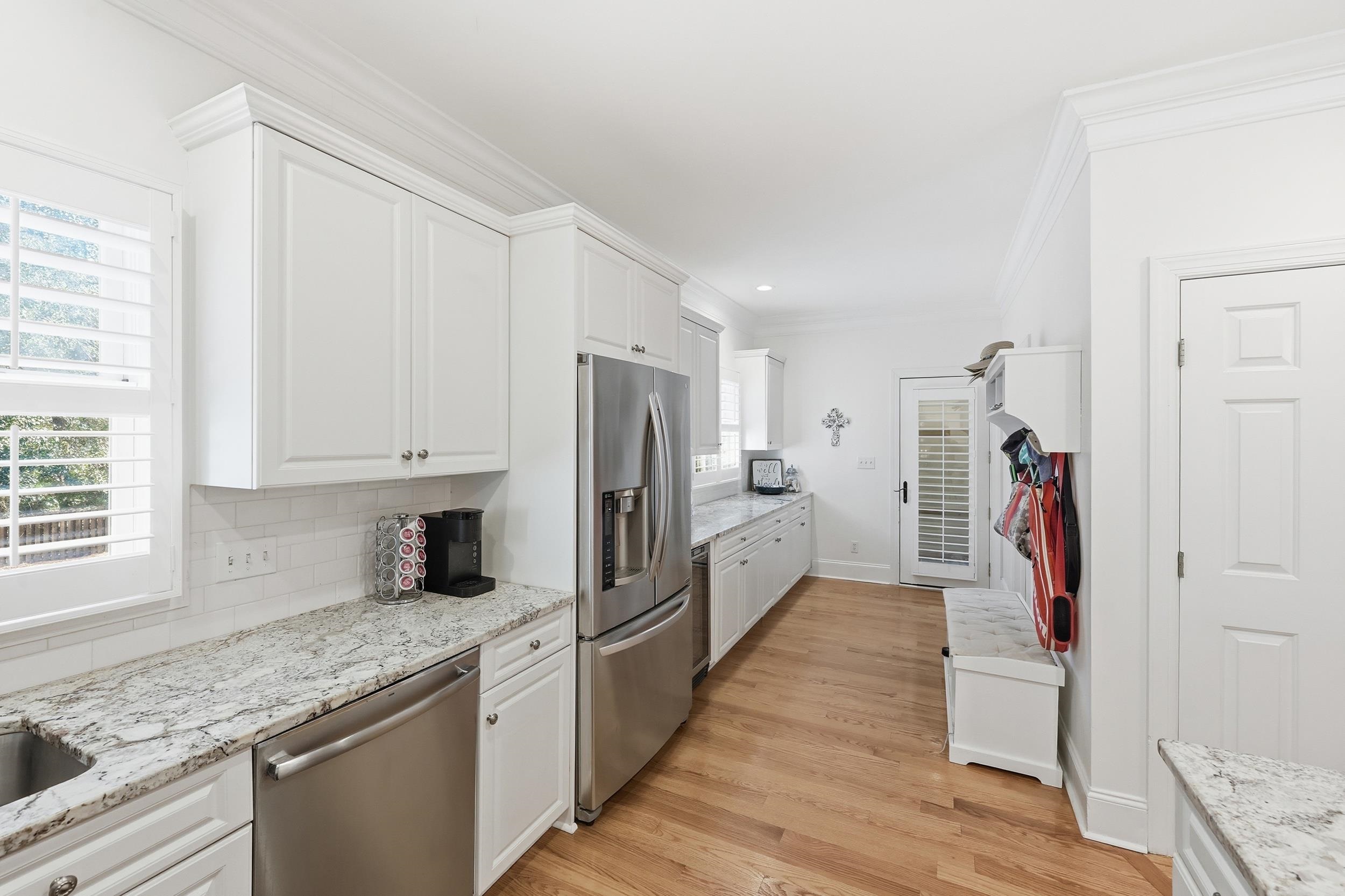 213 Old Carriage Loop Georgetown, SC 29440 - Photo 16 of 40 Kitchen featuring white cabinetry, appliances with stainless steel finishes, ornamental molding, light wood-style floors, and light stone countertops