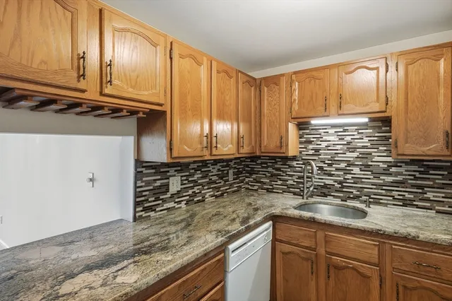 a kitchen with granite countertop stainless steel appliances a sink window and cabinets