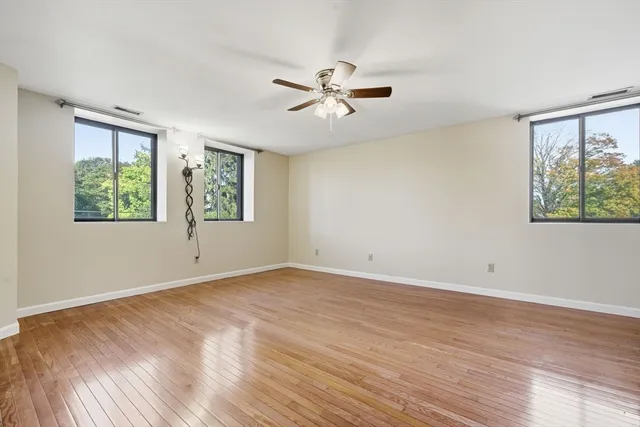 a view of empty room with wooden floor and fan
