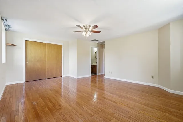an empty room with wooden floor and a ceiling fan
