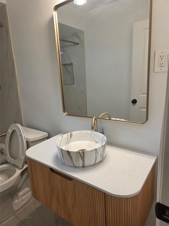 2108 Blake Avenue Dallas, TX 75228 - Photo 10 of 13 Secondary bathroom with modern floating vanity with a fluted wood-finish facade, a white countertop, and a circular vessel sink with a marble-like pattern