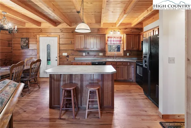 a kitchen with stainless steel appliances granite countertop a table chairs and a refrigerator