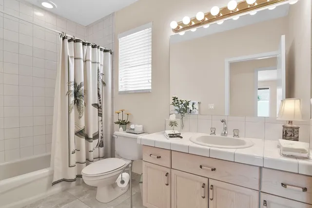 a bathroom with a toilet a sink a mirror a bathtub and shower