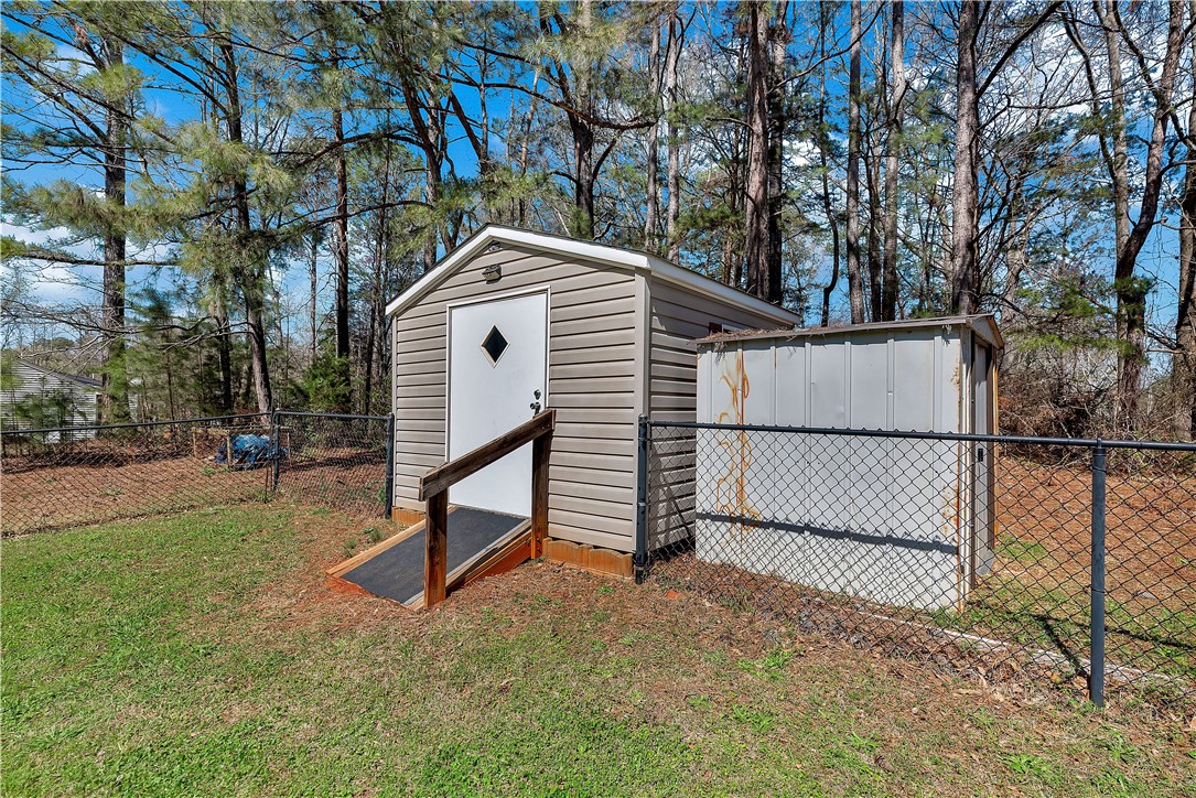 3338 Centerville Road Anderson, SC 29625 - Photo 26 of 28 This fenced outdoor space features practical storage buildings amidst natural surroundings, perfect for utility.