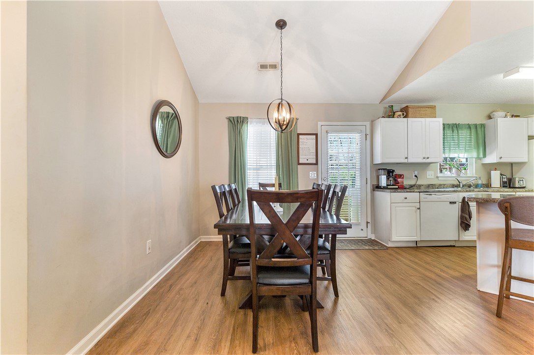 3338 Centerville Road Anderson, SC 29625 - Photo 7 of 28 This inviting space combines dining and kitchen areas, featuring a vaulted ceiling and rich hardwood flooring.