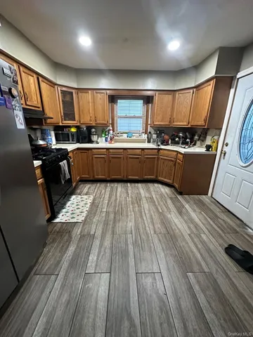 a kitchen with stainless steel appliances wooden floors wooden cabinets a sink and a stove