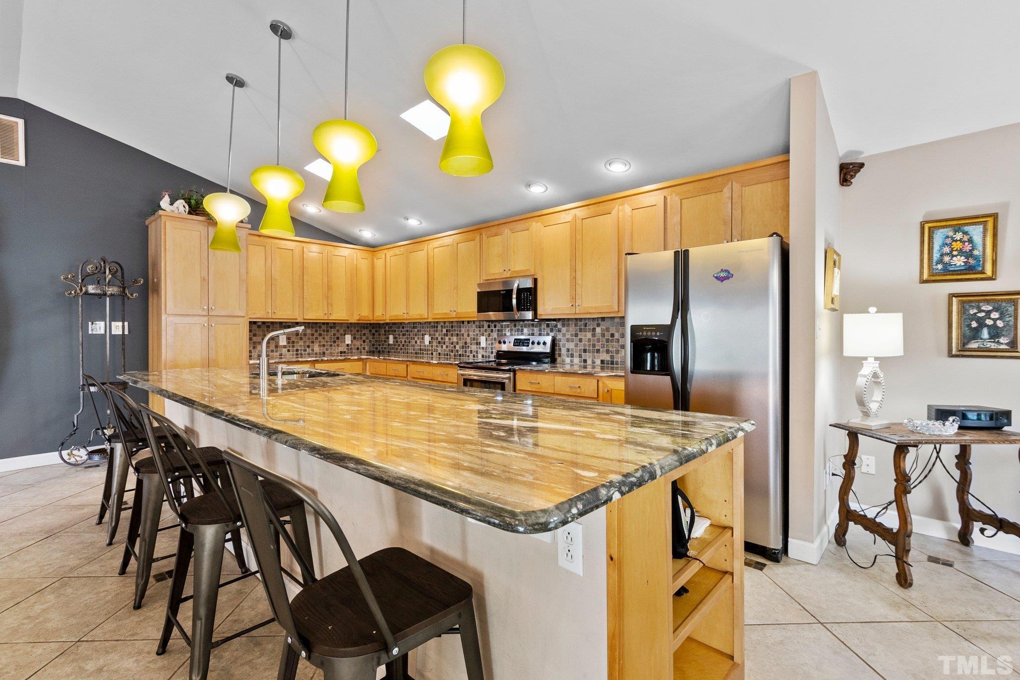 2704 Rue Sans Famille Raleigh, NC 27607 - Photo 11 of 43 a kitchen with stainless steel appliances granite countertop a table chairs and a refrigerator