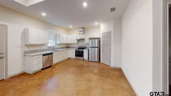 a kitchen with stainless steel appliances granite countertop a refrigerator stove and white cabinets