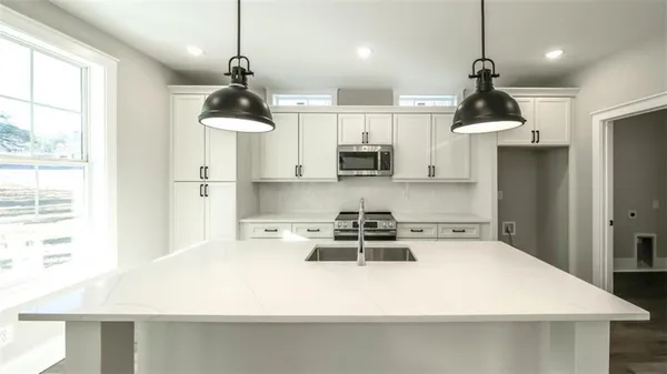 a kitchen with stainless steel appliances a stove a refrigerator a sink and white cabinets