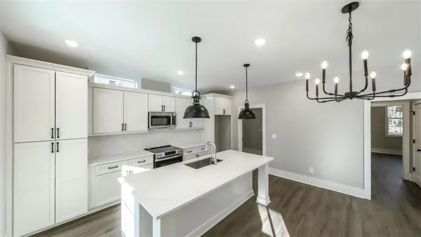 a kitchen with kitchen island a refrigerator a stove a sink and a wooden floor