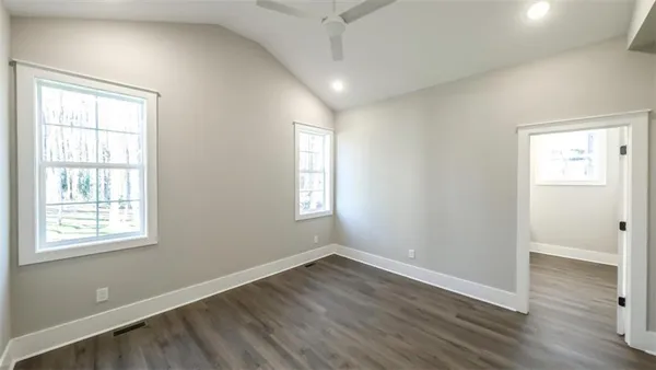 an empty room with wooden floor and windows
