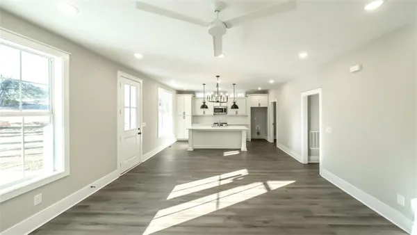 a large white kitchen with kitchen island a sink wooden floor and a large window