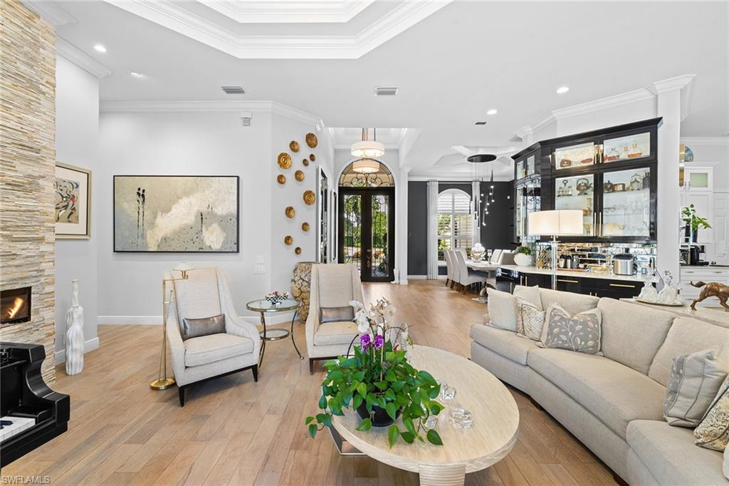 7837 Classics Drive Naples, FL 34113 - Photo 12 of 50 Living room featuring recessed lighting, light wood-style flooring, crown molding, french doors, and a stone fireplace