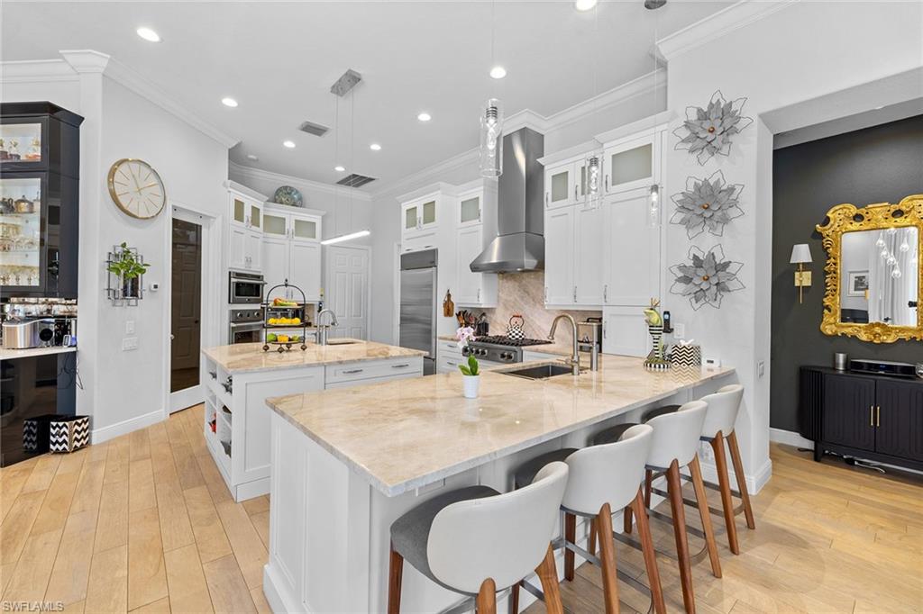 7837 Classics Drive Naples, FL 34113 - Photo 17 of 50 Kitchen with light wood-type flooring, a peninsula, backsplash, a kitchen breakfast bar, and recessed lighting